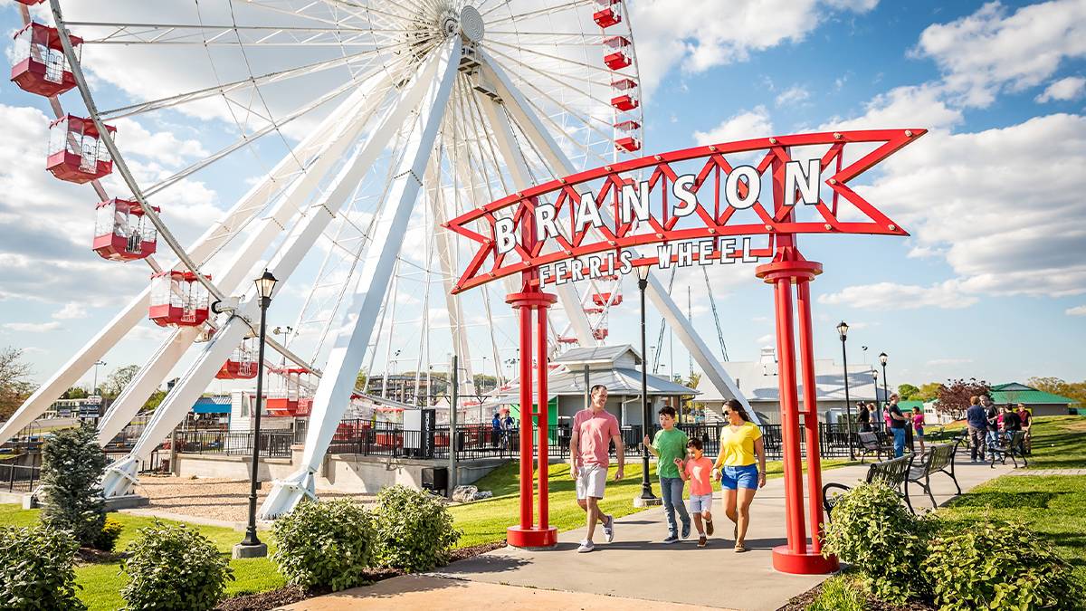 Ground view of the Branson Ferris Wheel and a family walking out of the attraction under the sign in Branson, Missouri, USA
